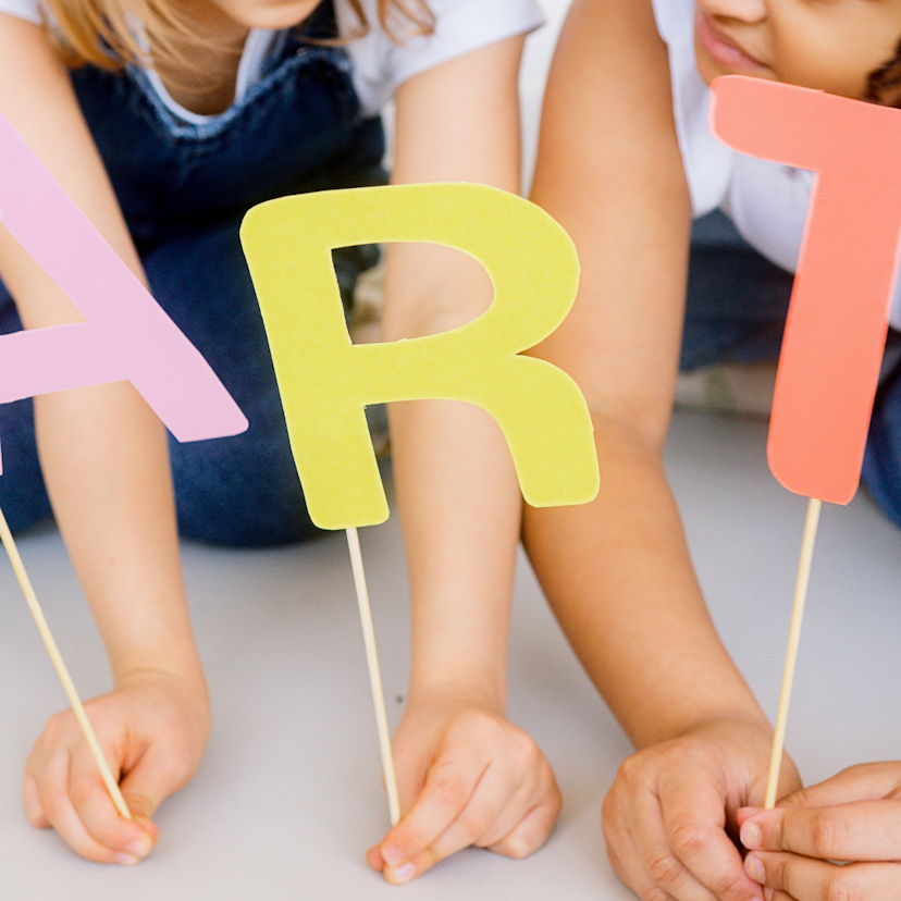 Young children holding up letters that spell art