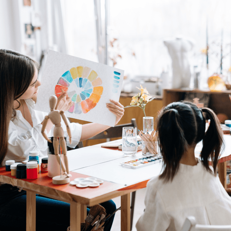 A teachers holding up a painted colour chart to a child student.
