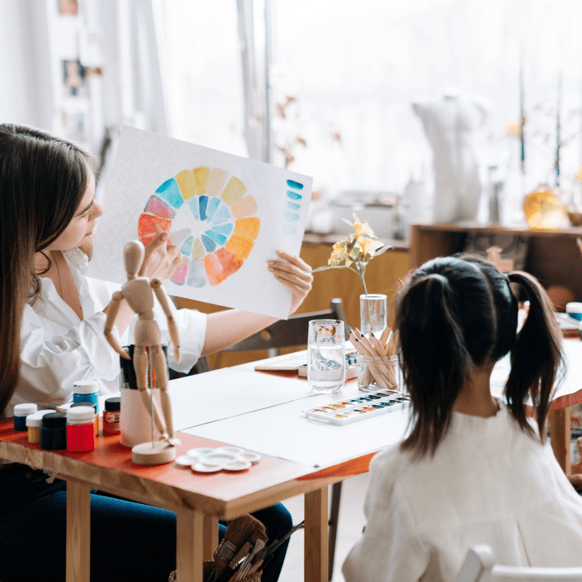 A teachers holding up a painted colour chart to a child student.