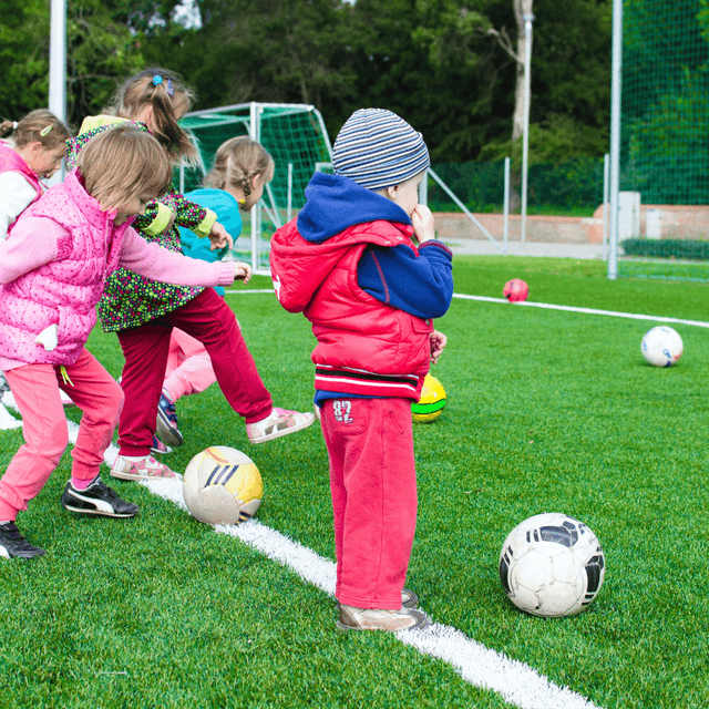 Toddlers kicking balls into goals